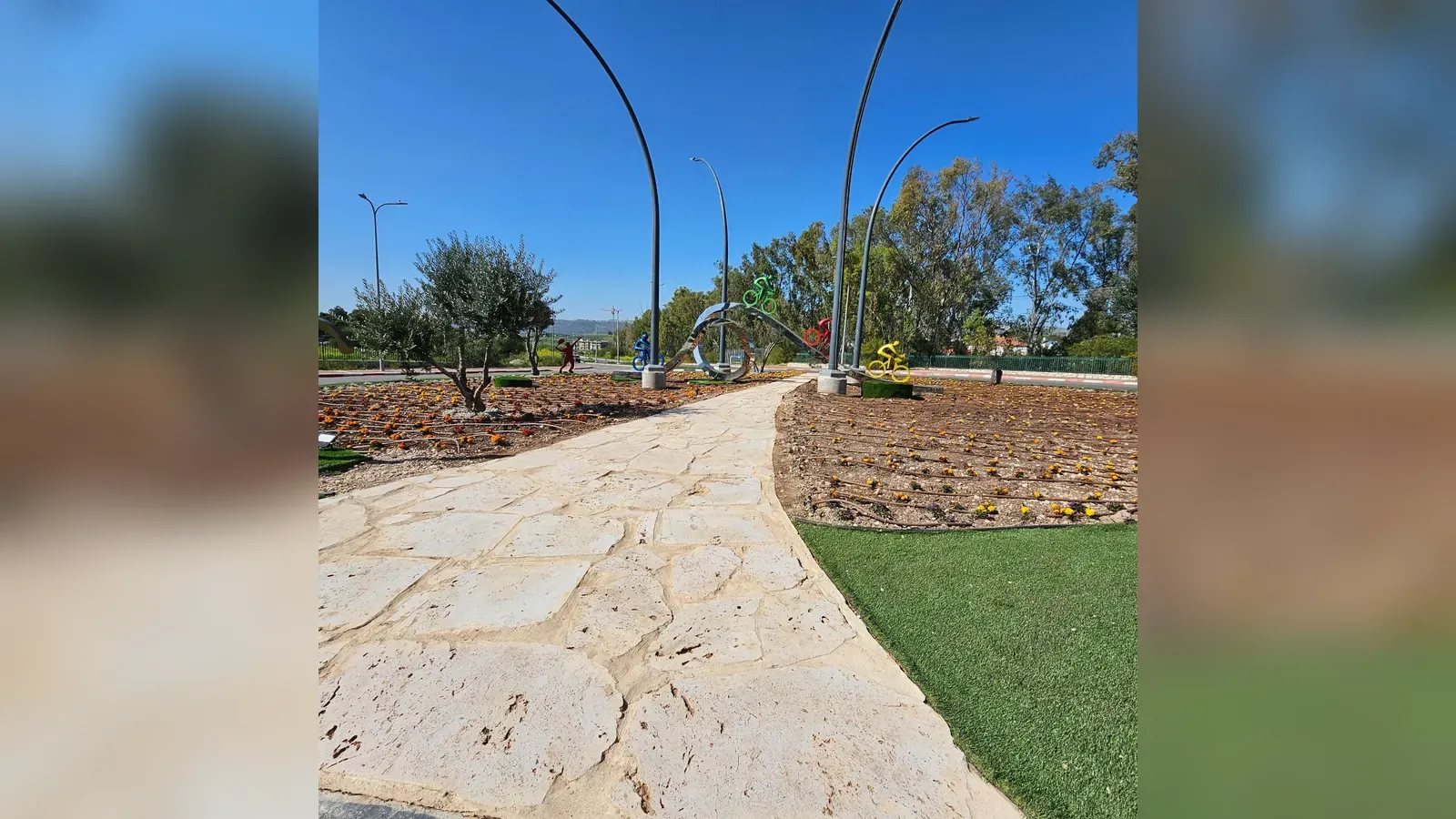 כיכר הספורט בעפולה לאחר הביצוע - שביל אבן טבעית, עמודי תאורה מעוקלים וערוגות מחופות